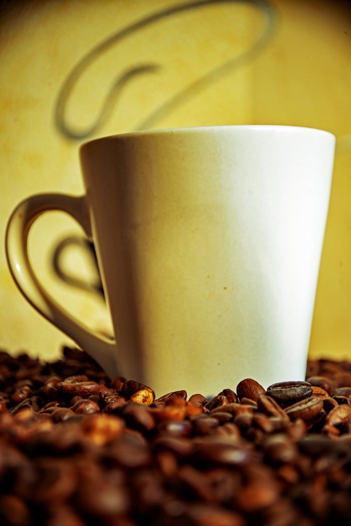 A white coffee mug surrounded by aromatic coffee beans, perfect for a cozy ambiance.