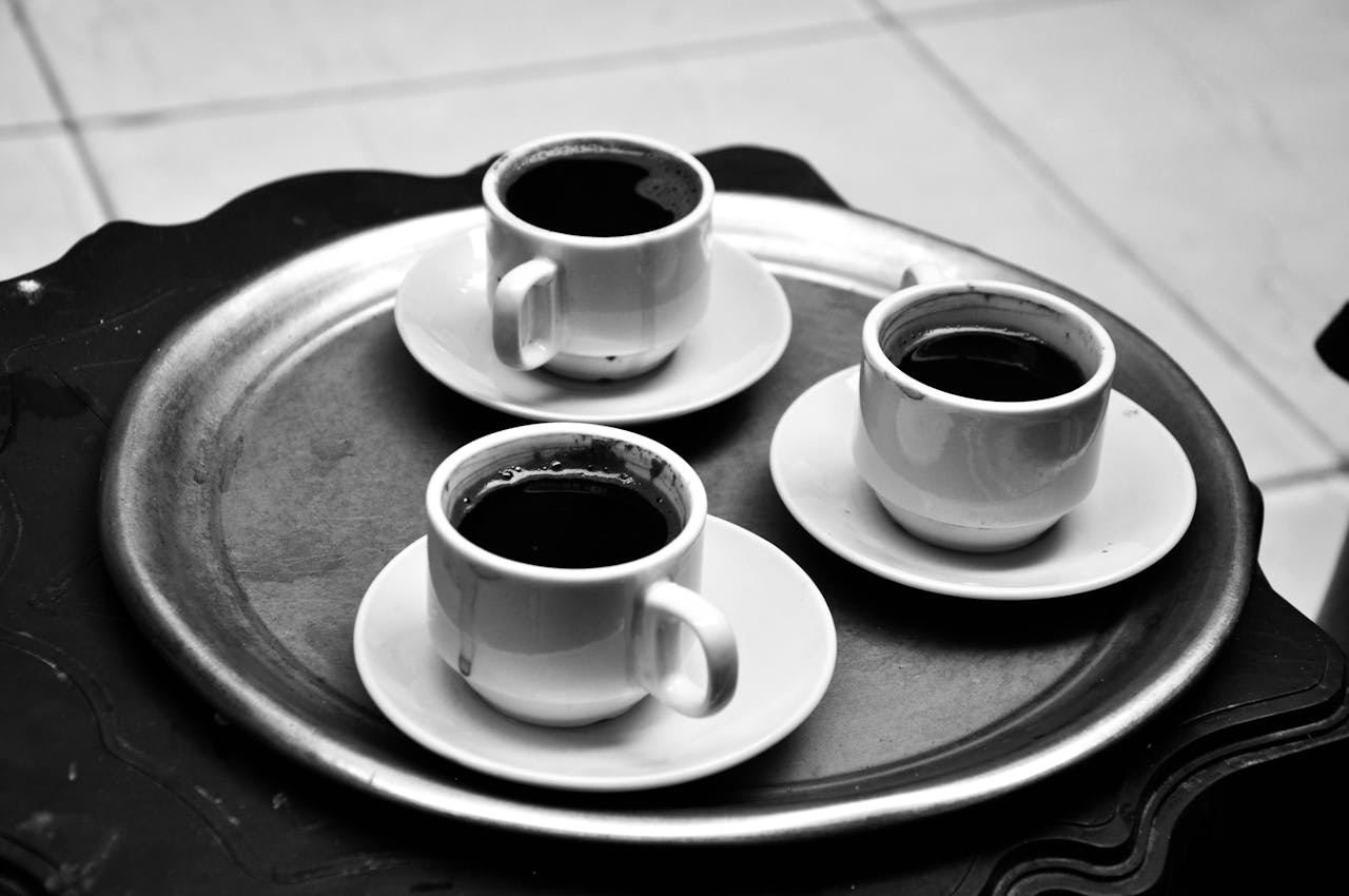 Three coffee cups placed on a tray, captured in a classic black and white style.
